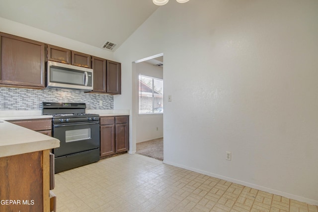 kitchen with visible vents, stainless steel microwave, black gas range oven, light countertops, and decorative backsplash