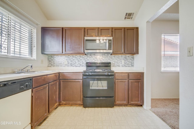 kitchen featuring stainless steel microwave, black gas stove, visible vents, dishwasher, and light countertops