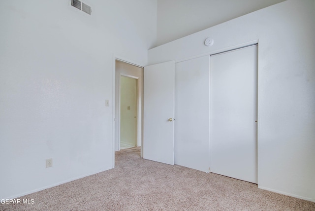 unfurnished bedroom featuring visible vents, a closet, and light carpet