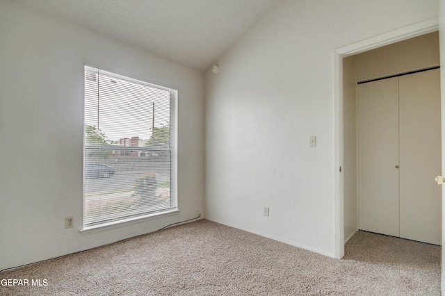 unfurnished bedroom featuring carpet and vaulted ceiling