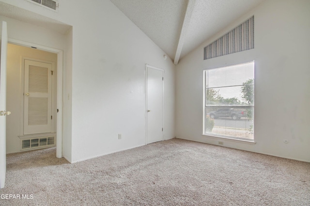 carpeted empty room with visible vents, a textured ceiling, and vaulted ceiling