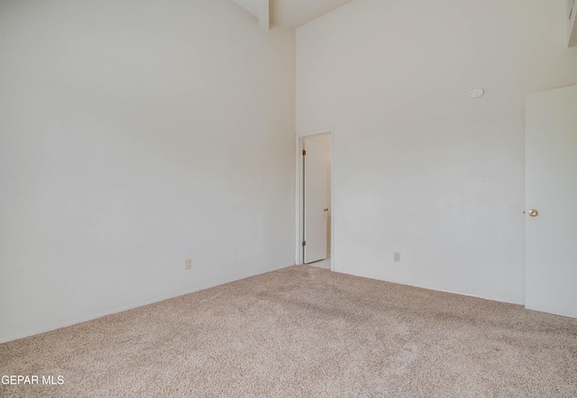 unfurnished room with beam ceiling, a towering ceiling, and carpet floors