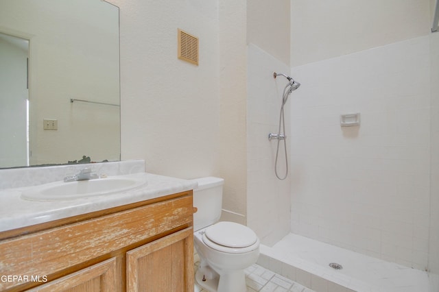 bathroom with visible vents, tiled shower, toilet, and vanity