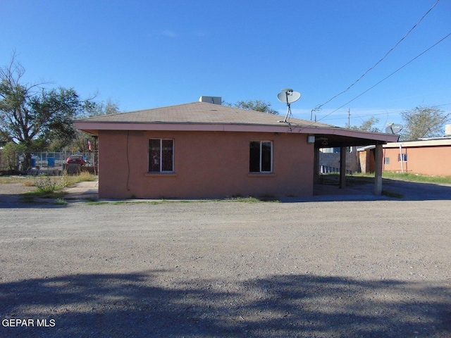 view of side of home with an attached carport and stucco siding