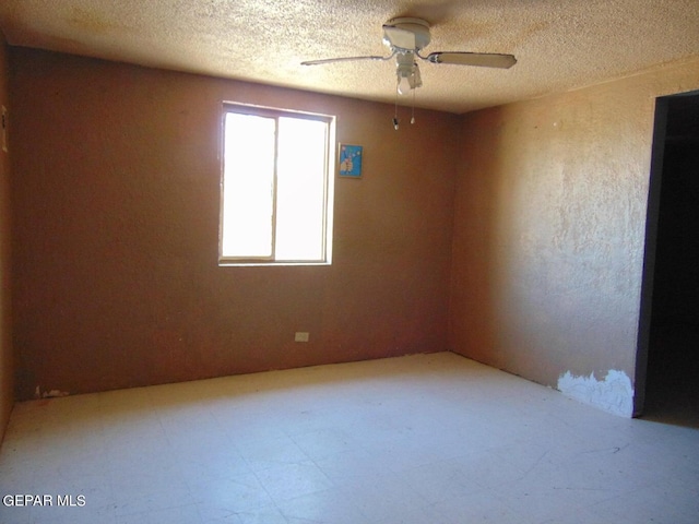 tiled empty room featuring ceiling fan and a textured ceiling