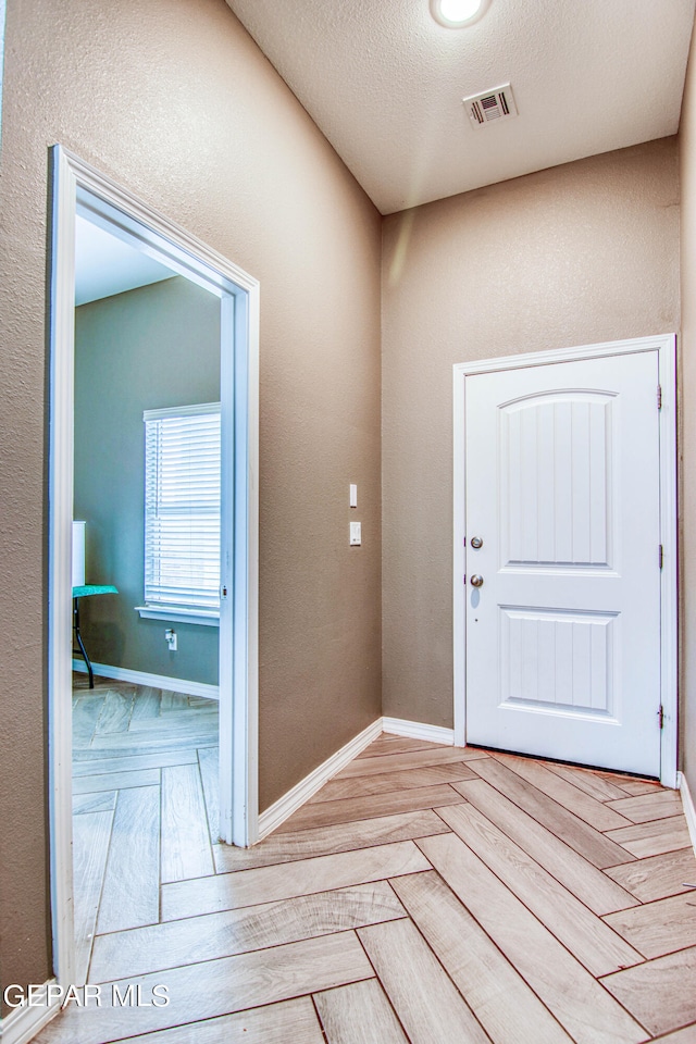 foyer with light parquet flooring and a textured ceiling