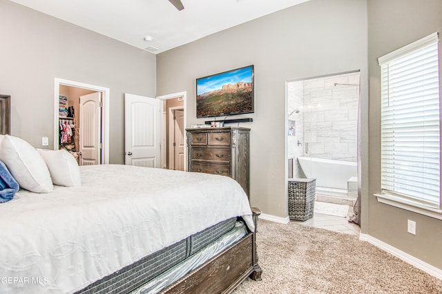 tiled bedroom featuring a spacious closet, ceiling fan, and ensuite bath