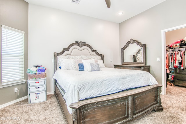 carpeted bedroom with a walk in closet, a closet, and ceiling fan