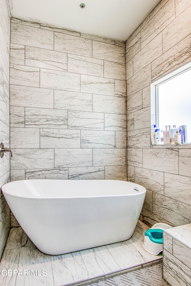 bathroom with a washtub and tile walls