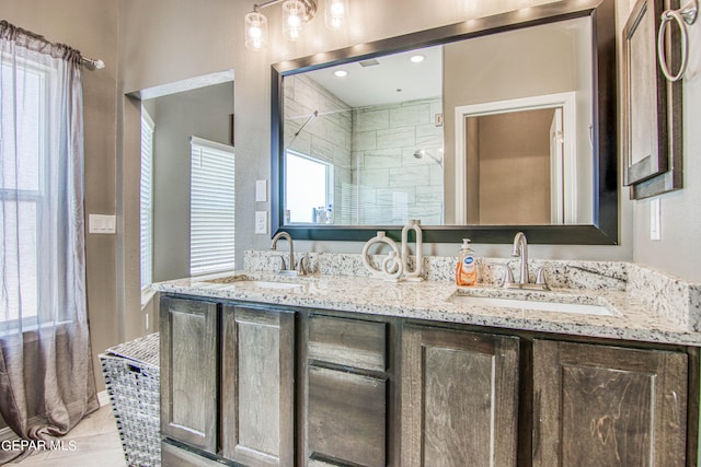 bathroom with a tile shower, vanity, and tile patterned floors