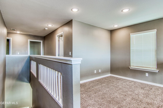 hall featuring carpet and a textured ceiling