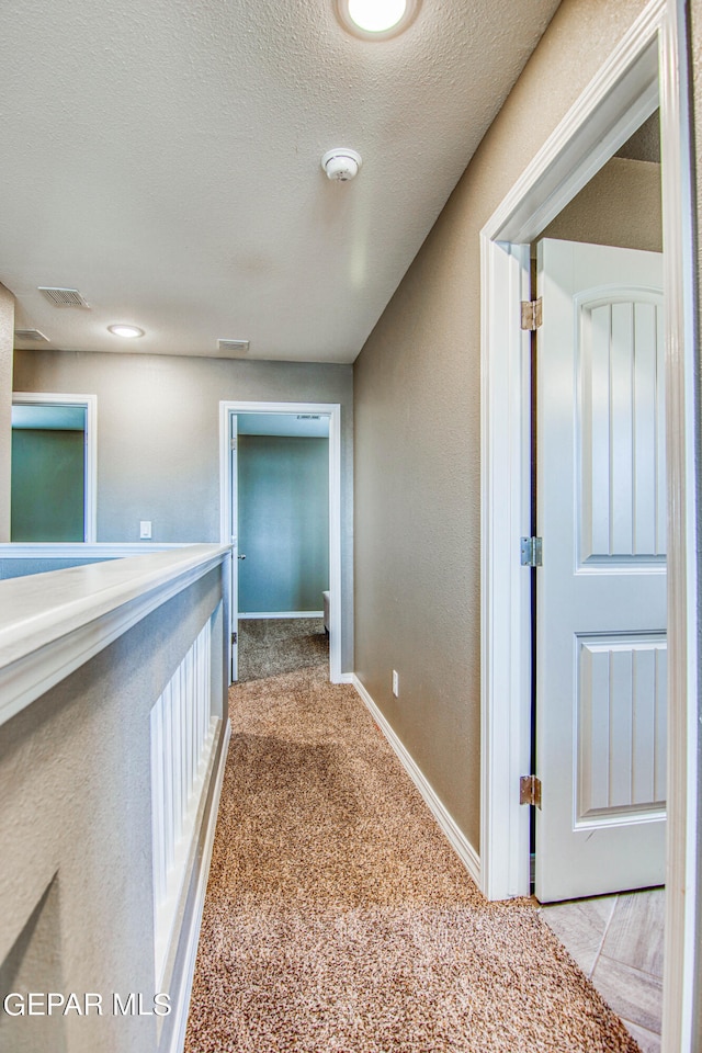 corridor featuring carpet floors and a textured ceiling