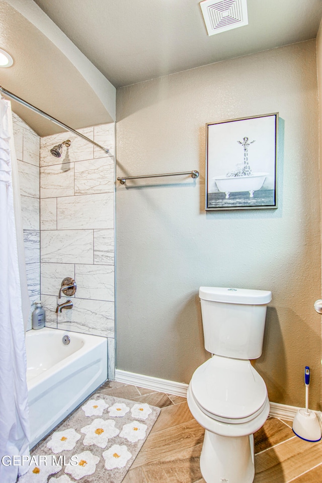 bathroom with hardwood / wood-style flooring, shower / bath combination with curtain, and toilet