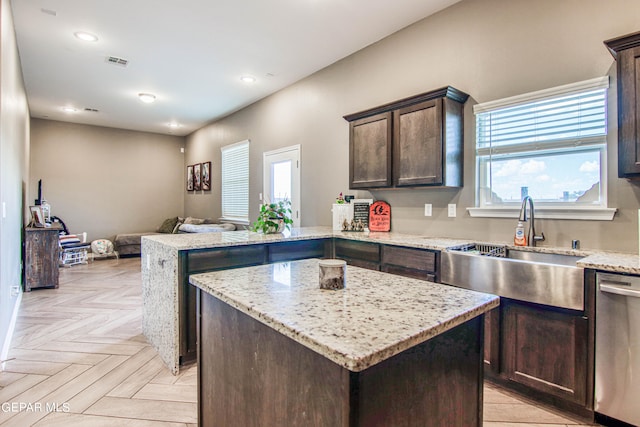 kitchen featuring stainless steel dishwasher, light parquet flooring, light stone countertops, sink, and a center island