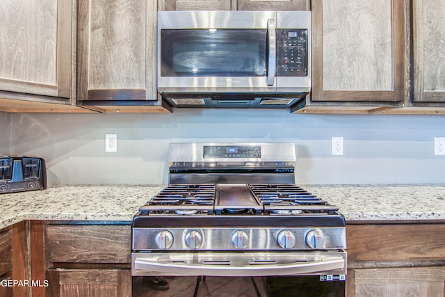 kitchen with appliances with stainless steel finishes and light stone countertops