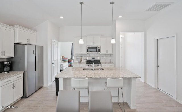 kitchen featuring tasteful backsplash, visible vents, appliances with stainless steel finishes, white cabinets, and a sink