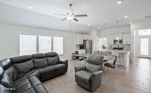 living room with light wood-type flooring, ceiling fan, and lofted ceiling