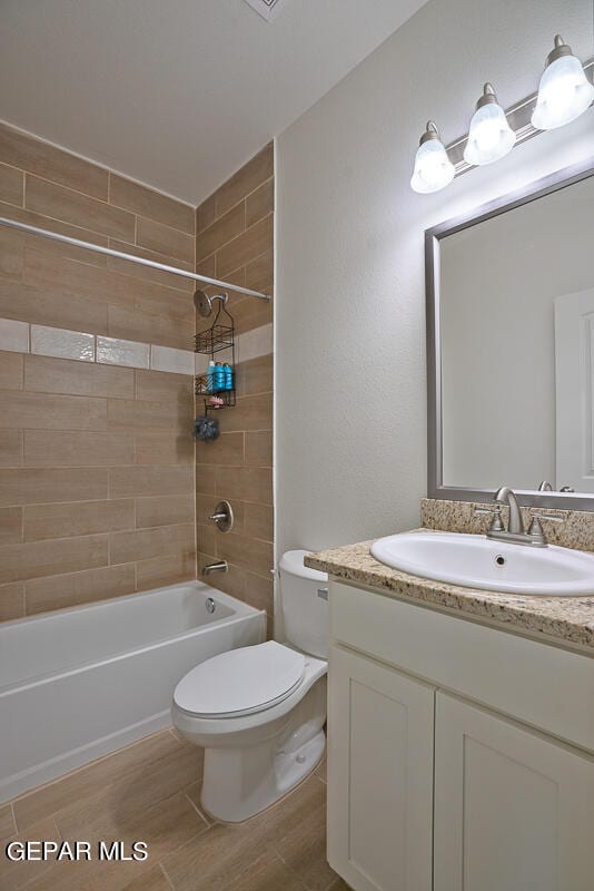 full bathroom featuring tiled shower / bath, vanity, and toilet