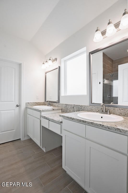 bathroom featuring an enclosed shower, vaulted ceiling, and vanity