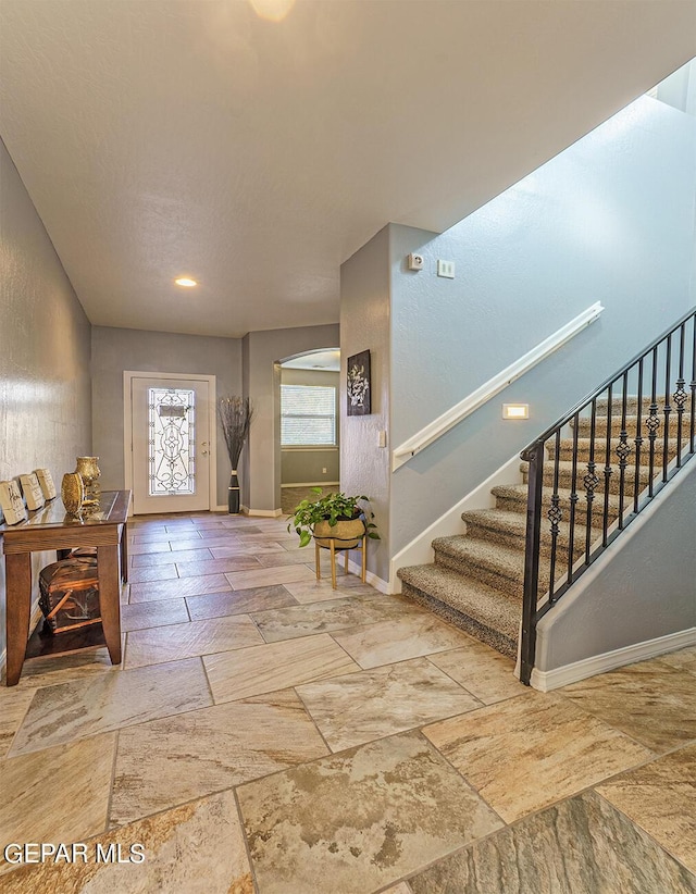 entrance foyer with baseboards, stairway, and stone tile floors