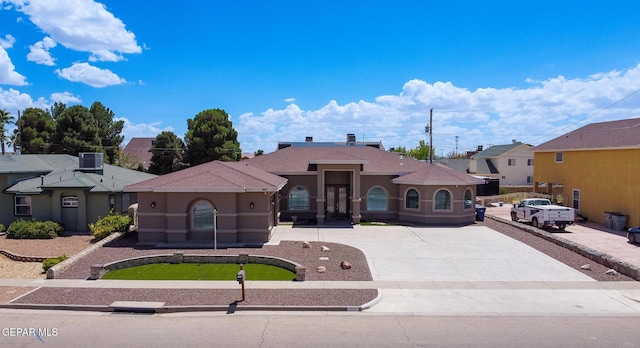 view of front facade featuring driveway, cooling unit, and stucco siding