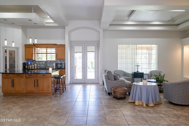 living room featuring light tile patterned floors, a tray ceiling, beam ceiling, and french doors