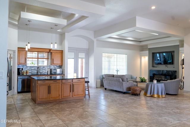 kitchen with a premium fireplace, open floor plan, dishwasher, dark countertops, and a raised ceiling