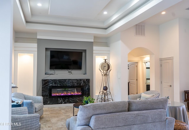 living area with arched walkways, recessed lighting, visible vents, a high ceiling, and a high end fireplace