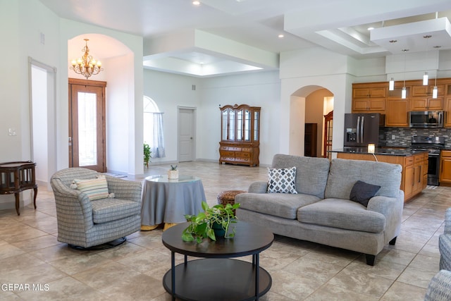 living room featuring a high ceiling, arched walkways, a raised ceiling, and a chandelier