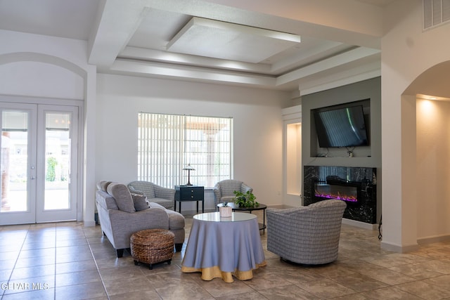 living area featuring french doors, a wealth of natural light, a premium fireplace, and visible vents