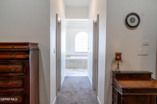 corridor with carpet floors, a textured wall, and baseboards