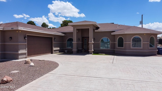 view of front of property with a shingled roof, decorative driveway, an attached garage, and stucco siding