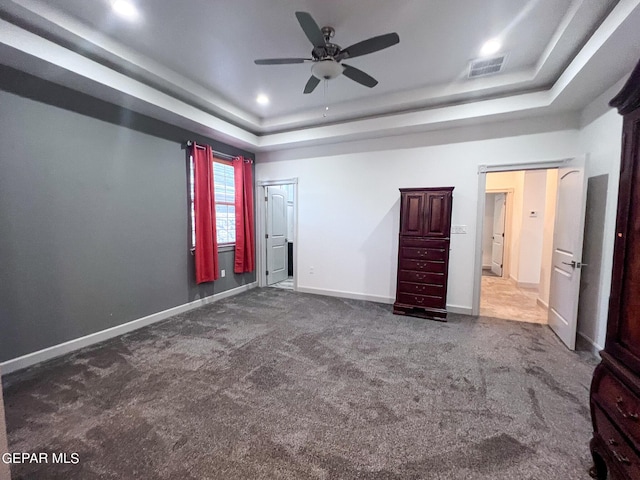 carpeted empty room featuring ceiling fan, recessed lighting, visible vents, baseboards, and a raised ceiling