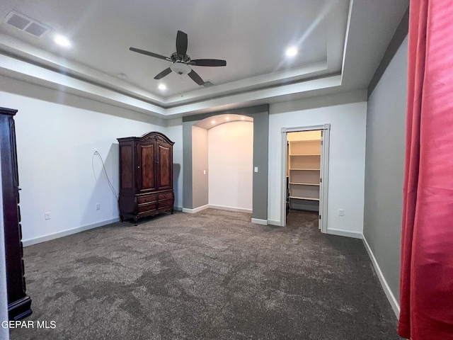 unfurnished bedroom with baseboards, visible vents, arched walkways, a tray ceiling, and recessed lighting