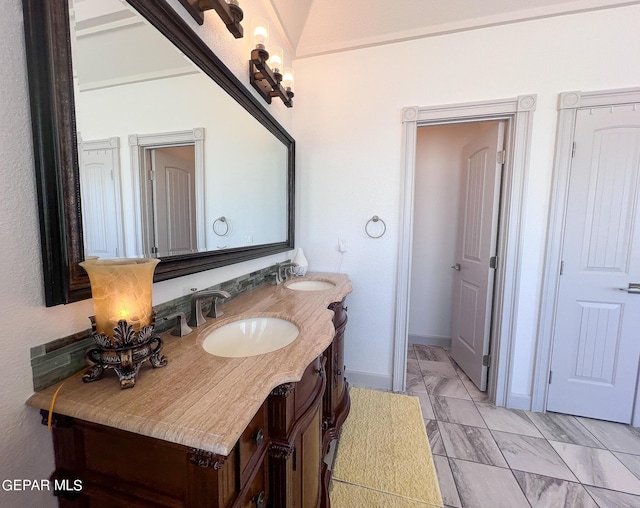 bathroom with marble finish floor, a sink, baseboards, and double vanity