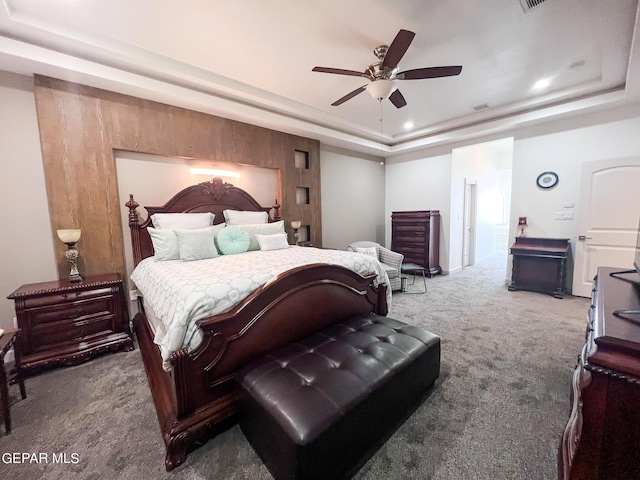 carpeted bedroom featuring a raised ceiling and a ceiling fan