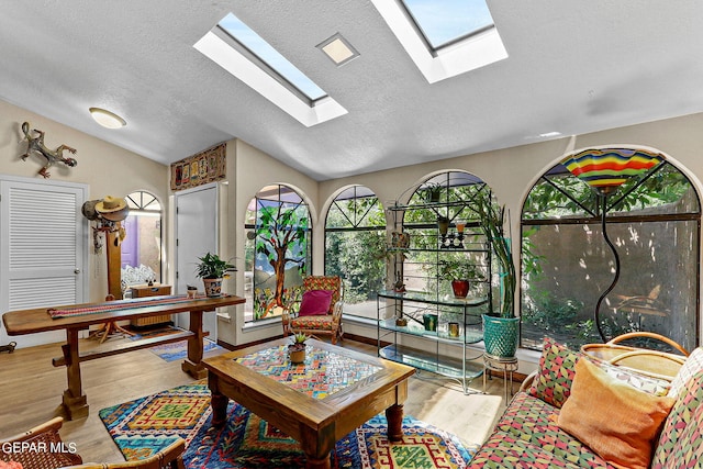 interior space featuring vaulted ceiling with skylight, a wealth of natural light, and wood finished floors