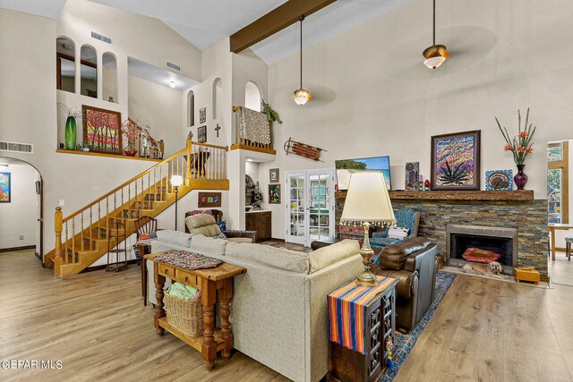 living room with light wood-type flooring, ceiling fan, beam ceiling, high vaulted ceiling, and a fireplace