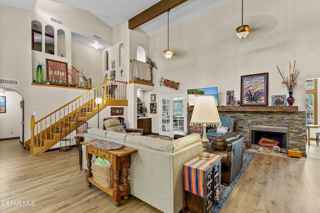 living room featuring a stone fireplace, wood finished floors, and visible vents