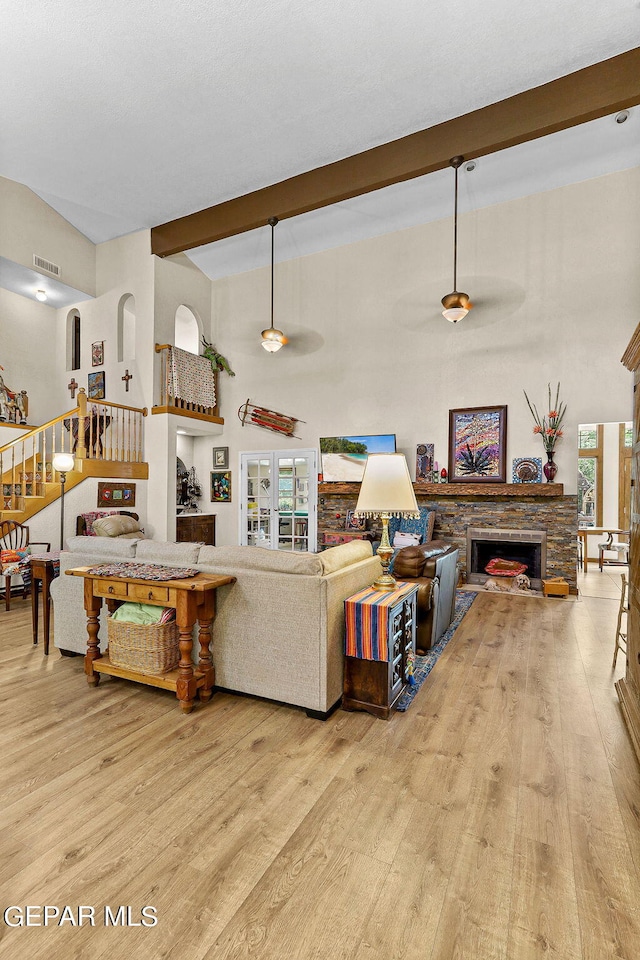 living area with visible vents, beamed ceiling, stairway, and light wood finished floors