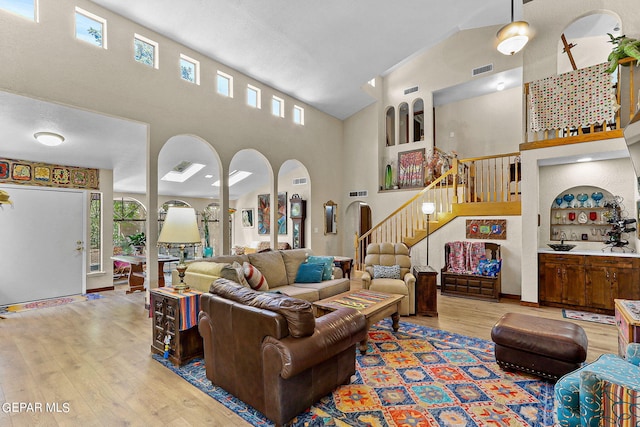 living room with built in features, a high ceiling, and light hardwood / wood-style flooring