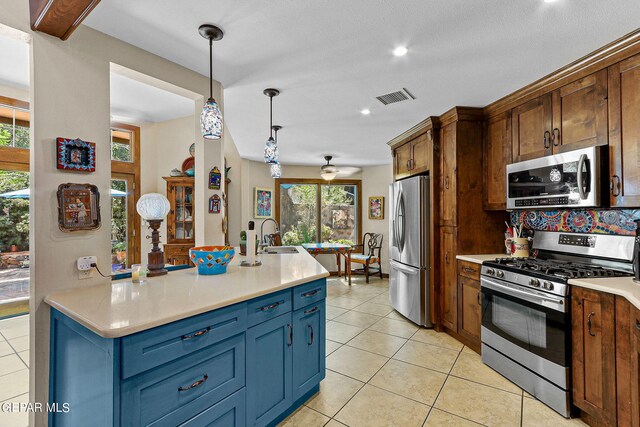 kitchen featuring decorative backsplash, stainless steel appliances, sink, light tile patterned floors, and hanging light fixtures