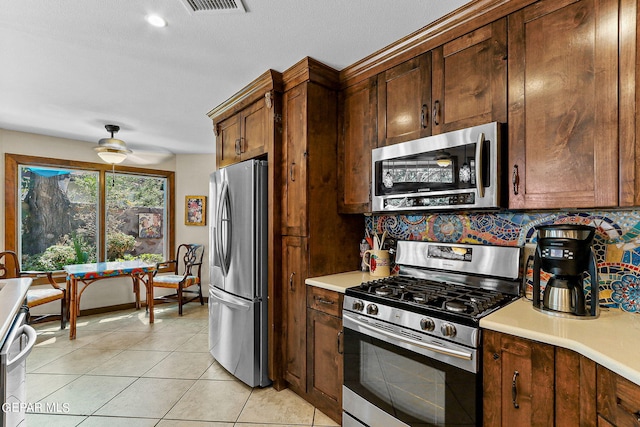 kitchen with ceiling fan, light tile patterned floors, appliances with stainless steel finishes, and tasteful backsplash