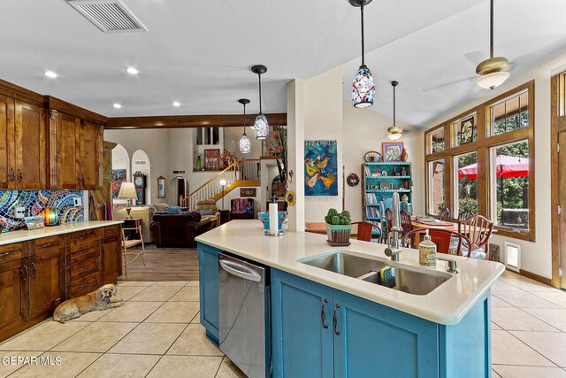 kitchen featuring dishwasher, sink, decorative light fixtures, a center island with sink, and light tile patterned floors