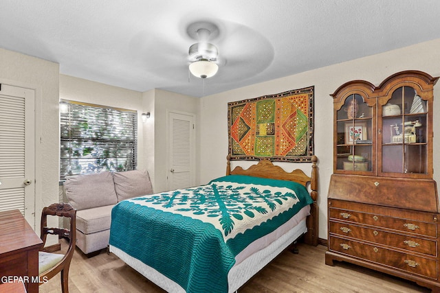 bedroom featuring light wood-style floors, ceiling fan, and a textured ceiling