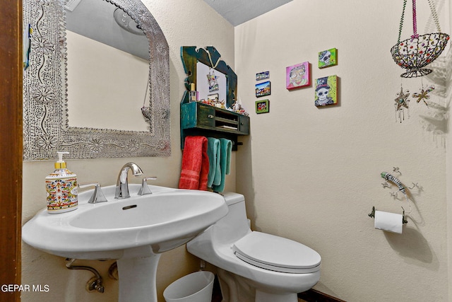 bathroom featuring toilet and a textured wall