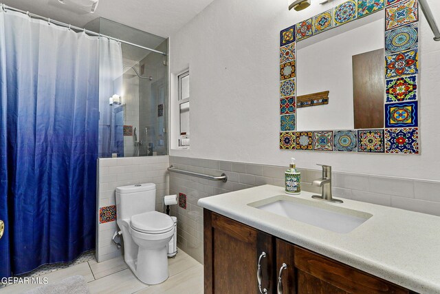 bathroom with vanity, a shower with shower curtain, tile walls, and toilet