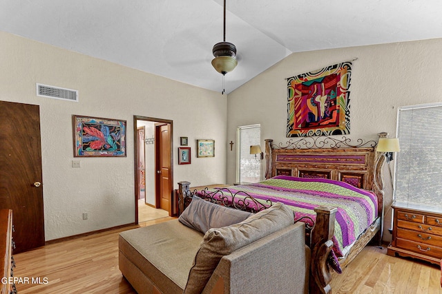 bedroom with visible vents, a ceiling fan, a textured wall, vaulted ceiling, and light wood-style floors