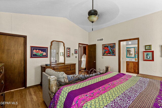 bedroom with hardwood / wood-style floors, ceiling fan, connected bathroom, and vaulted ceiling