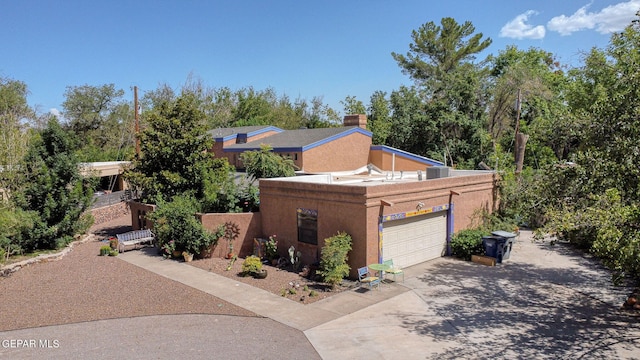 view of front of house featuring driveway, a chimney, and stucco siding